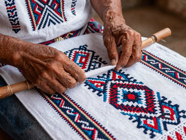Manos de un artesano orureño tejiendo un aguayo tradicional con patrones geométricos complejos