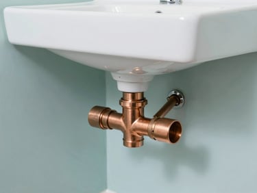Clean copper plumbing pipes neatly installed under a modern washbasin, bright work-light, sharp focus