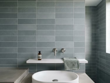 Straight-on architectural shot of a minimalist bathroom wall with perfectly aligned grey porcelain tiles and clean grout lines, bright natural daylight, sharp focus, 35mm