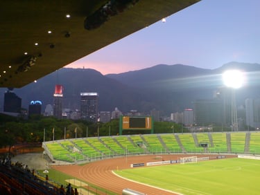 Estádio Olímpico de la UCV ao entardecer em Caracas, com vista ampla das arquibancadas e campo iluminado
