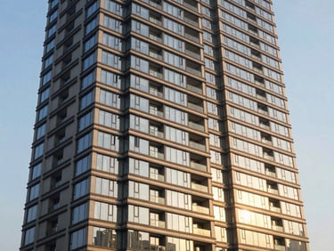 High-rise apartment building exterior, bright natural golden hour sunlight reflecting off glass panels.