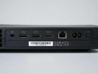 Crisp product photography of console ports and serial number label under bright diffused studio light, neutral light-grey background, sharp focus.
