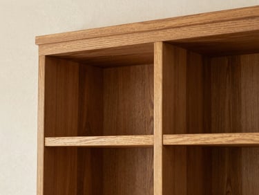Close-up of a custom oak built-in bookshelf integrated seamlessly into a plaster wall, showcasing tight wood joinery and natural grain