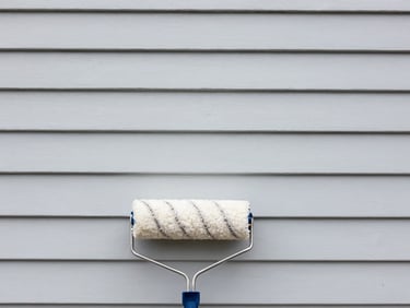 Smooth, freshly painted wall surface with a roller in the foreground, bright and even lighting, clean lines, high contrast.