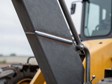 Macro shot of a clean, thick weld on a charcoal gray steel loader arm, sharp industrial photography, high-contrast.