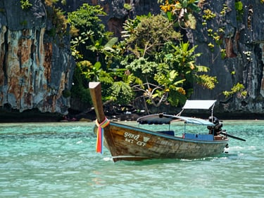 A traditional longtail boat on a turquoise sea in Thailand, limestone cliffs in the background, bright sunny day, lush tropical foliage.