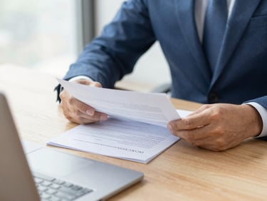 Close-up of an advisor reviewing plan documents on a wooden table, soft natural daylight, professional editorial style