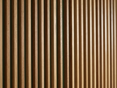 Elegant interior wall clad in premium thin wood slats, warm lighting highlighting the seamless gaps and natural color variations