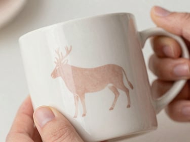 Close-up of a Scandinavian-inspired vinyl decal applied to a ceramic mug, hands smoothing out the vinyl, soft diffused daylight, matte finish.