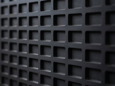 Macro shot of a matte black carbon-fiber 3D printed structural wall, showcasing clean layer lines and precise geometric infill.