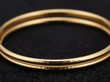 Extreme close-up of solid 22k gold bangles with intricate hand-beaten textures, sharp gold reflections against dark velvet