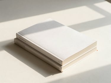A stack of three modern paperback books with clean minimalist covers, casting soft shadows on a creamy surface