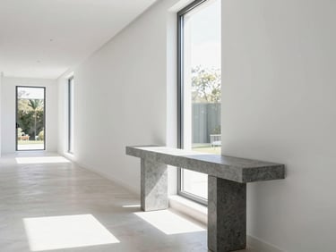 Bright editorial photography of a beautifully lit modern villa hallway, clean white walls, minimalist slate-gray console table, soft morning daylight streaming through a tall window, sharp focus.