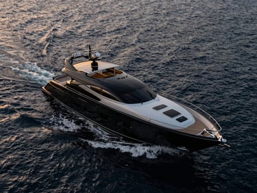 Aerial view of a sleek black luxury yacht hull cutting through deep obsidian water at sunset