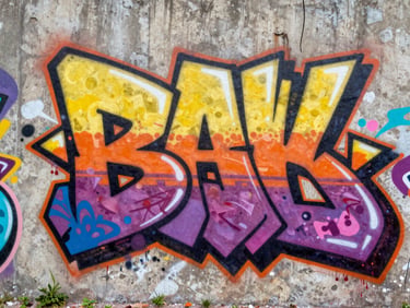 Close-up of a local artist spray painting a bold graffiti piece on a raw concrete wall in bright daylight, vibrant colors, 35mm lens.