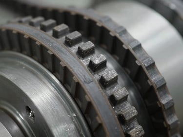 Extreme close-up of heavy-duty synchronous drive belts showing reinforced fiber teeth, clean industrial setting, sharp focus.