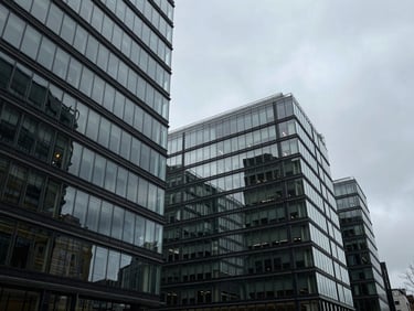 Wide-angle architectural crop of a contemporary glass office complex in London, cool overcast daylight, sharp geometric shadows, 35mm