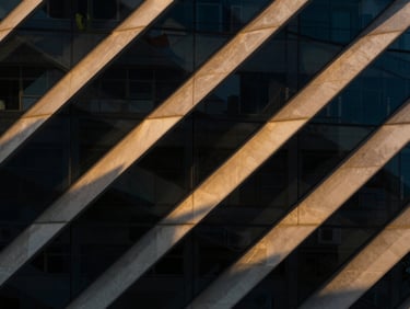 Abstract geometric glass structure converging under sharp architectural shadows, minimalist composition