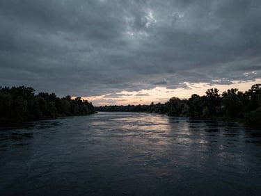 Stark atmospheric landscape of Ottawa river at dusk, moody overcast skies, high contrast, desaturated cool tones, cinematic framing