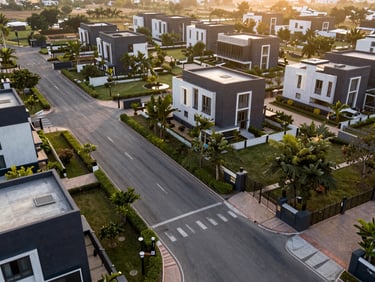 Wide-angle drone shot of a gated residential plot development in New Gurgaon, clean paved roads, manicured green borders.