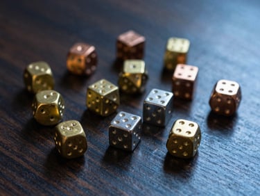Macro shot of a set of heavy metal dice (brass, copper, steel) scattered on a dark oak gaming table, shallow depth of field, warm side-lighting, deep blue and gold tones.