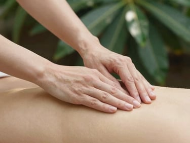 Close-up of hands gently hovering over the solar plexus area during a self-treatment, soft natural daylight, deep botanical greens and gold tones, shallow depth of field, 35mm.