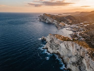 Cinematic aerial view of Andalusian coastline, golden hour light, deep blue ocean meeting white cliffs, sharp composition, 35mm lens