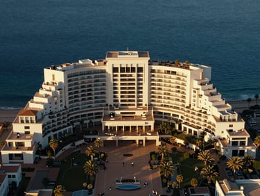 Cinematic aerial shot of a luxury coastal hotel in Malaga, golden hour, clear blue water, architectural symmetry