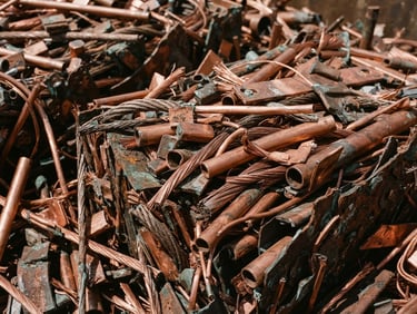 Macro shot of sorted copper scrap under harsh direct daylight, high-contrast metallic textures, sharp focus, 35mm.