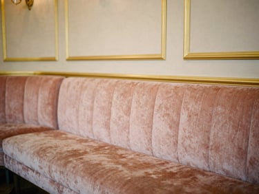 Intimate shot of a vintage velvet lounge area inside the hall, gold-leaf details on the walls, soft warm ambient light, 35mm editorial photography