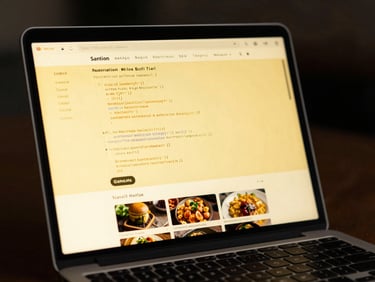 Close-up of a modern laptop screen showing clean code and a local Malaysian restaurant website mockup, dramatic yellow screen-glow, dark background.