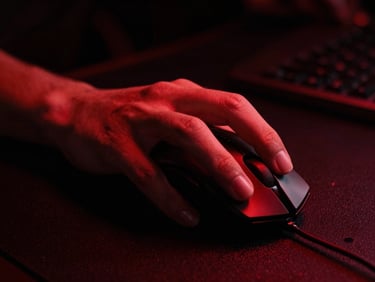 Extreme close-up of hands on a gaming mouse in a dark industrial gaming station, dramatic red backlighting, high-contrast dark shadows, 35mm lens