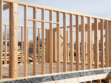 Crisp timber framing structure on a construction site, bright natural Alberta daylight, high-contrast slate and timber tones, sharp focus, 35mm lens.