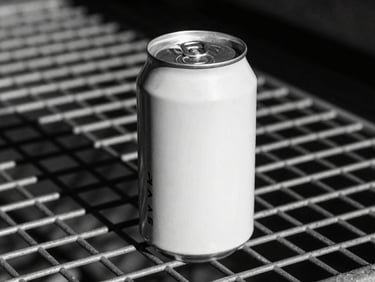 Stark close-up of a printed aluminum can mockup sitting on a raw metal grid, harsh sunlight, deep dramatic shadows.