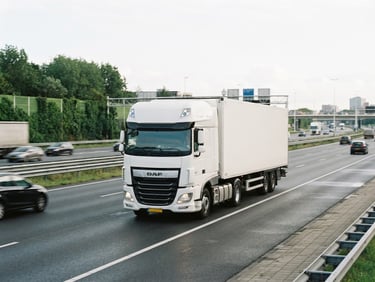 A clean white modern transport truck driving on a wide Dutch highway under bright overcast daylight, sharp focus, 35mm photography.