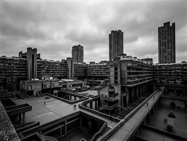 Extreme wide environmental shot of a monolithic concrete brutalist structure with sharp geometric lines, harsh shadows, under a cold, overcast sky. Focus on the scale and starkness.