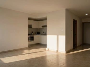 Living area of a one-bedroom apartment in São Paulo, afternoon sunlight casting warm light across a tiled floor, open kitchen visible, clean and practical finishes
