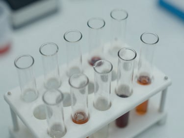 Close-up overhead view of laboratory test tubes and a specimen rack on a clinical white surface, even diffuse light, no people