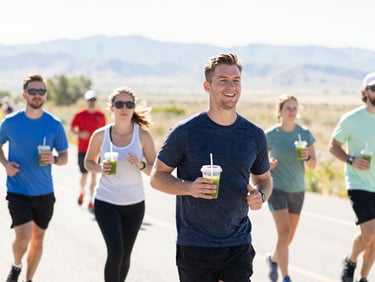 Bright environmental shot of a community running event in Utah, sunny morning light, active people holding green juice cups