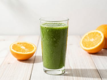 Vibrant green smoothie in a condensation-beaded glass on a clean light wood table, fresh sliced citrus fruits nearby, bright natural morning daylight, shallow depth of field