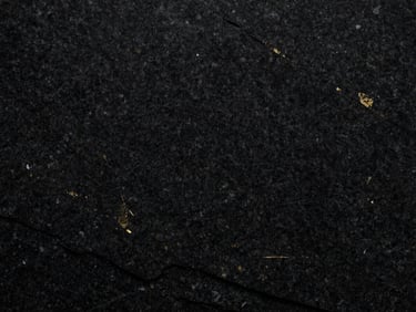 Deep black granite slab with subtle gold mineral flecks, macro texture