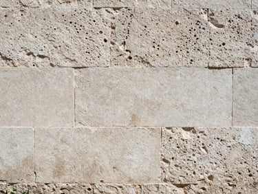 Textured historic stone wall with clean mortar joints, sunlight emphasizing the rough hand-chiseled limestone blocks, gritty documentary photography, 35mm