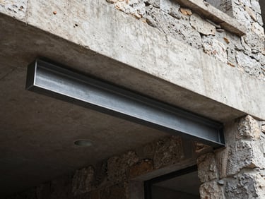 A steel IPN beam cleanly installed beneath a raw concrete lintel in a renovated building, gritty documentary style, high contrast daylight, 35mm