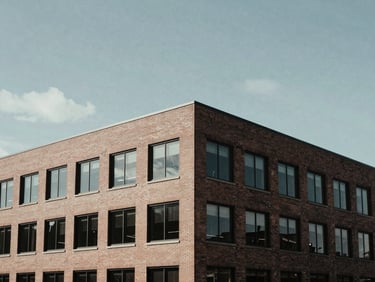 Architectural shot of a modern, low-profile brick office building in Alexandria under overcast daylight, clean lines, cinematic shadows.