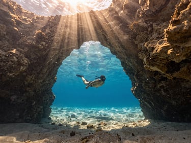 A diver swimming through a natural limestone underwater arch in deep blue Mediterranean water, sun rays piercing through the surface, high contrast, warm editorial photography
