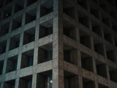 Low-key dramatic night shot of a geometric concrete building facade in Tokyo, subtle cyan light leak, 35mm