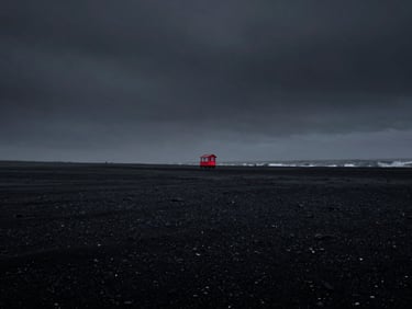 Desaturated black sand beach in Iceland under a dark heavy sky, low-key lighting, 35mm
