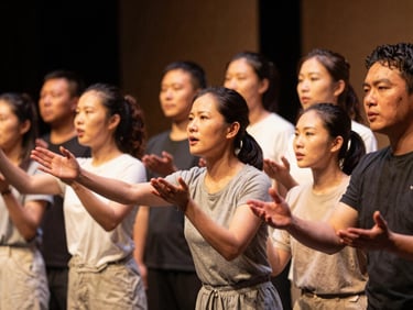 Warm editorial photography of an intergenerational group staging a theater performance, soft ambient amber stage lighting, expressive faces collaborating, shallow depth of field