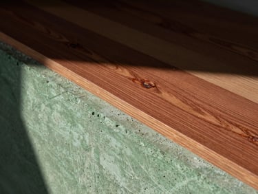 Extreme close-up of raw concrete and walnut wood material transitions in an empty sunlit interior, deep shadows, 35mm.
