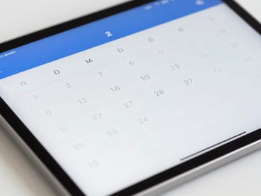 Close-up of a digital calendar interface on a sleek tablet, showing patient appointments, clean editorial photography, bright natural daylight, surgical blue accents, sharp focus.